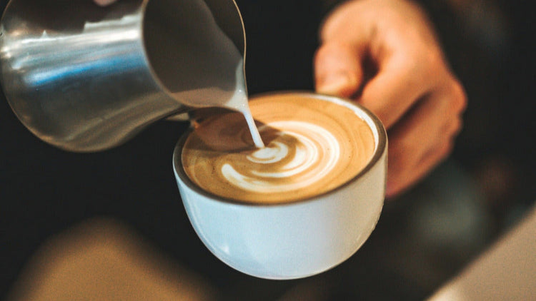 Barista pouring coffee from metal jug into cup with coffee art Espresso Nation Roasters specialty coffee Narraweena Northern Beaches Sydney NSW