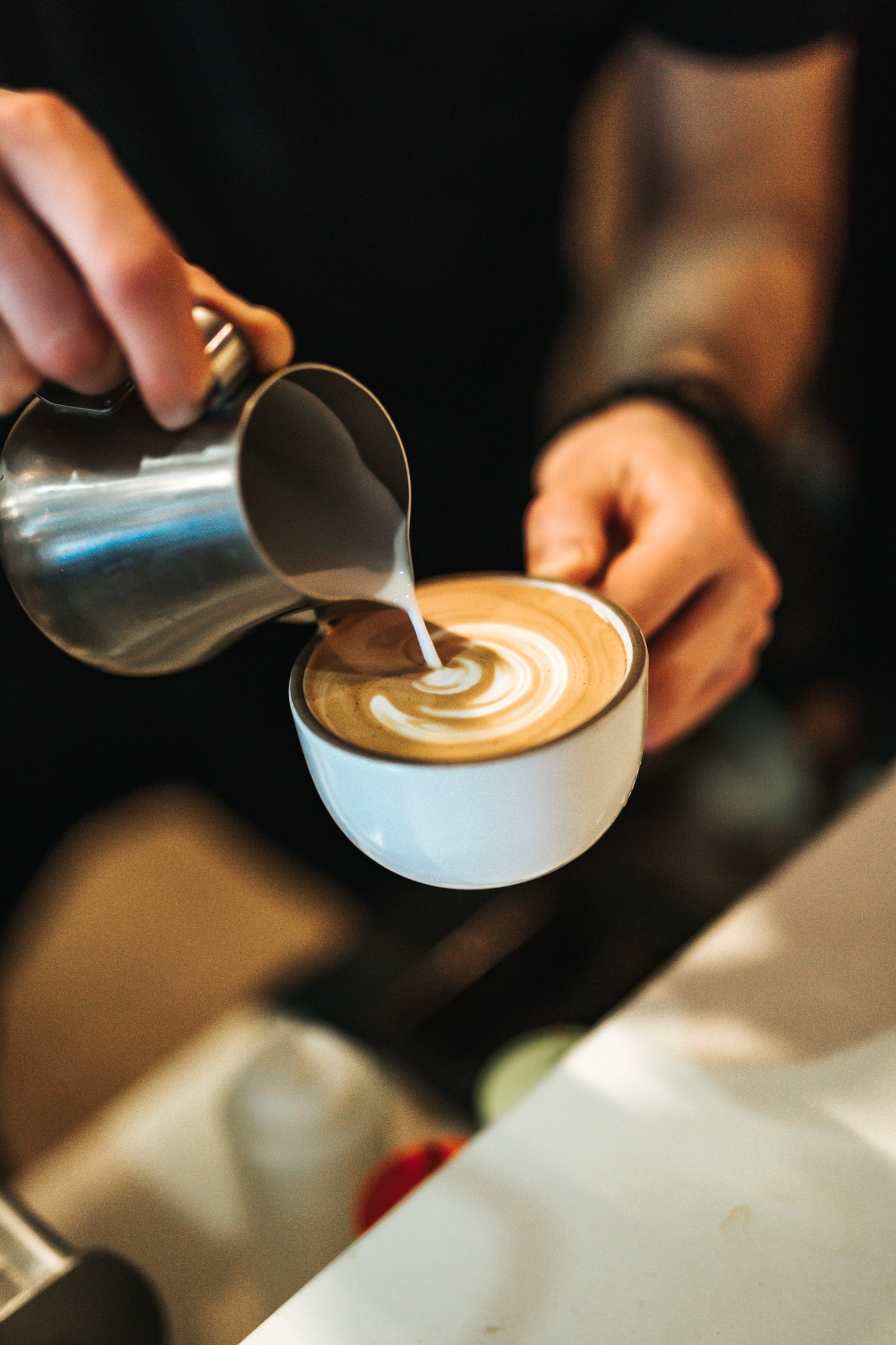 Barrister pouring coffee from metal jug into cup with coffee art Espresso Nation